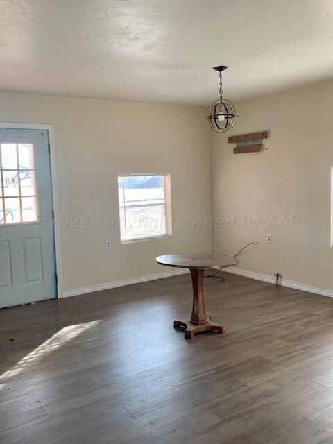 unfurnished dining area featuring dark hardwood / wood-style flooring, a notable chandelier, and a healthy amount of sunlight