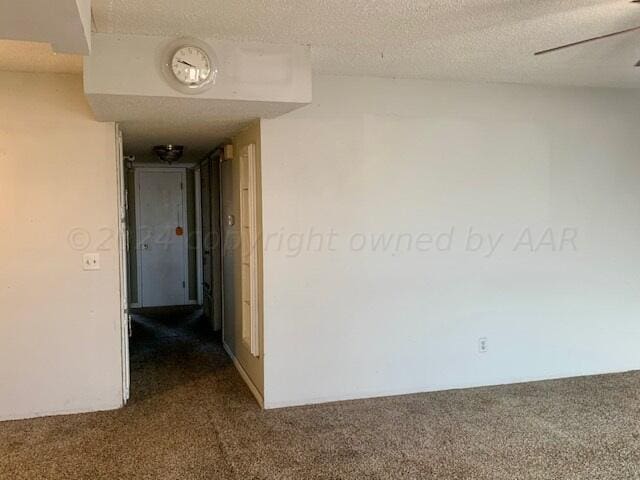 hallway featuring carpet flooring and a textured ceiling