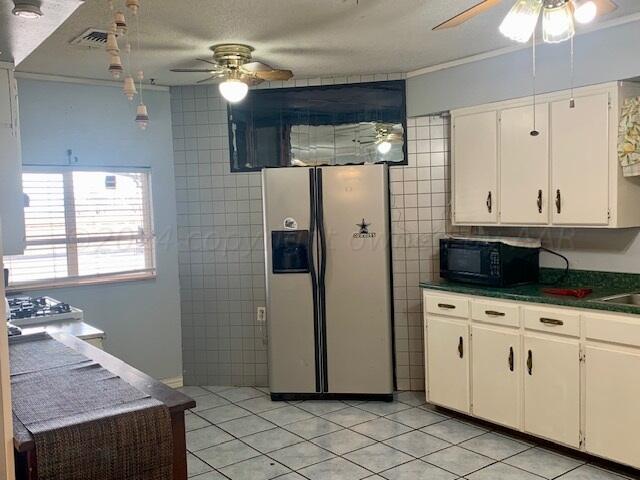 kitchen with ceiling fan, light tile patterned floors, stainless steel fridge, and white cabinets