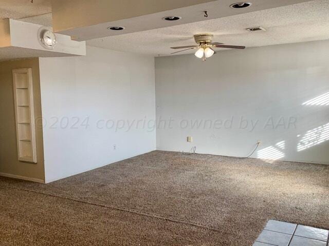 spare room featuring a textured ceiling, carpet, and ceiling fan