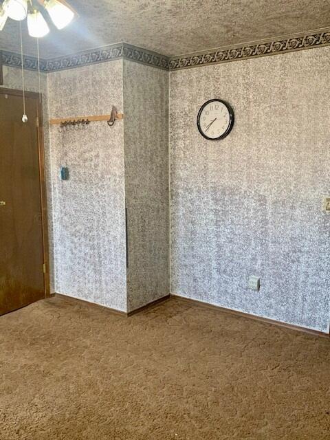 carpeted empty room featuring a textured ceiling and ceiling fan