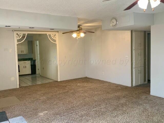 carpeted spare room with ceiling fan and a textured ceiling