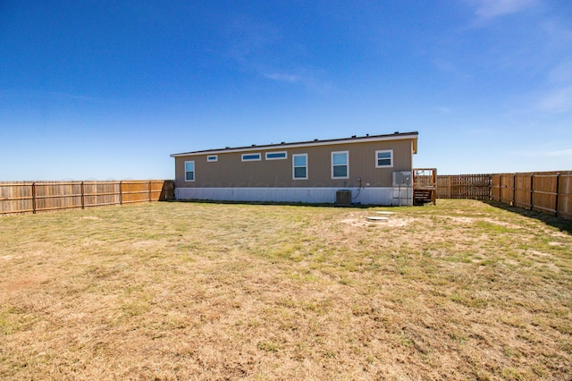 rear view of house featuring cooling unit and a yard