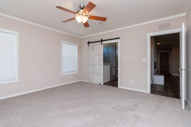 unfurnished bedroom with carpet flooring, a barn door, connected bathroom, ceiling fan, and crown molding