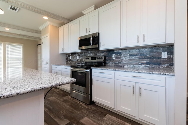 kitchen featuring dark hardwood / wood-style flooring, white cabinets, ornamental molding, and stainless steel appliances