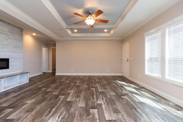 unfurnished living room with dark hardwood / wood-style flooring, a tray ceiling, ornamental molding, and plenty of natural light