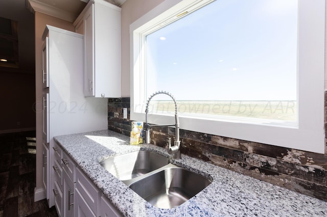 kitchen with plenty of natural light, sink, light stone counters, and ornamental molding