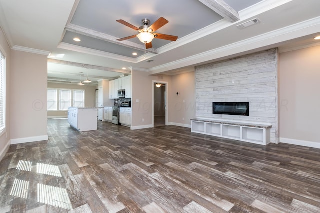 unfurnished living room featuring ornamental molding, ceiling fan, a fireplace, a raised ceiling, and dark hardwood / wood-style flooring