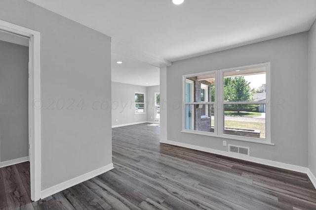 empty room featuring dark wood-style floors, baseboards, visible vents, and recessed lighting