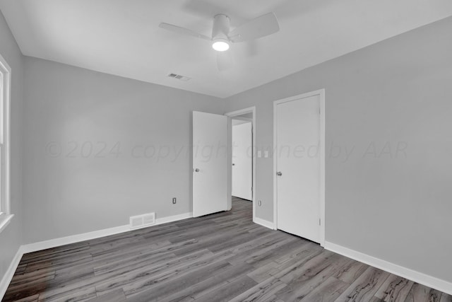 unfurnished room featuring baseboards, visible vents, and wood finished floors