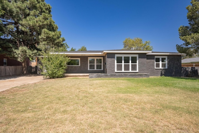 rear view of property featuring a lawn and fence