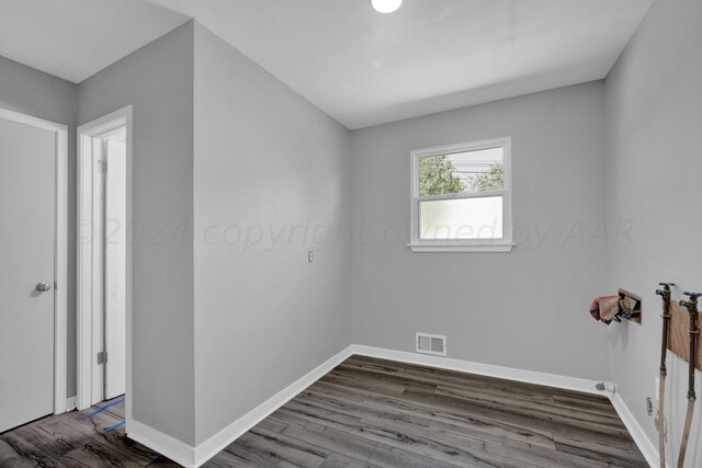 unfurnished room with visible vents, baseboards, and wood finished floors