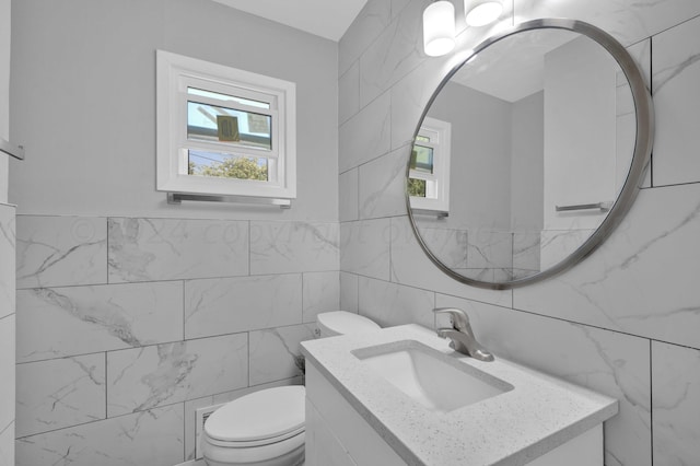 half bath with tile walls, toilet, and vanity