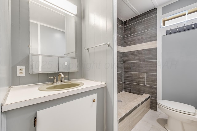 bathroom featuring toilet, tile patterned floors, tiled shower, and vanity
