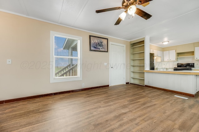 unfurnished living room with baseboards, ornamental molding, and wood finished floors