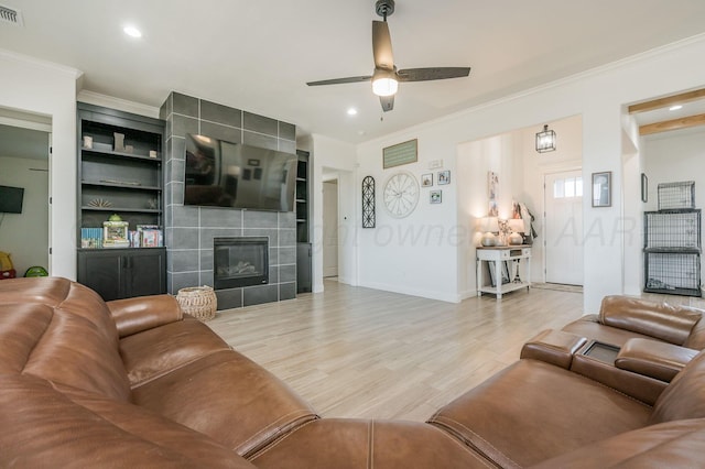 living area with light wood-style floors, visible vents, a fireplace, and ornamental molding