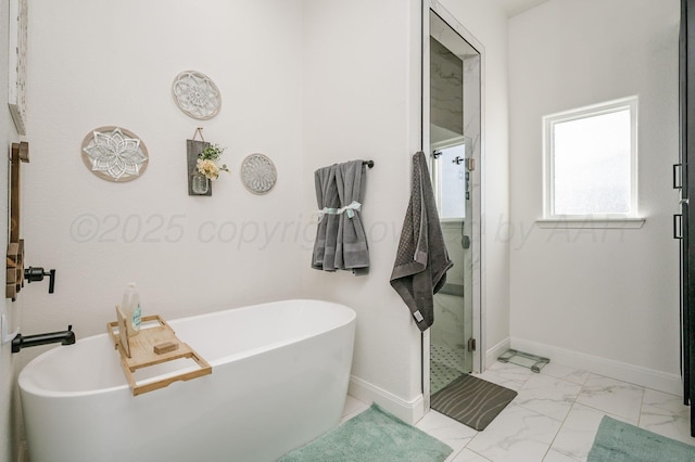 bathroom featuring marble finish floor, baseboards, a stall shower, and a soaking tub