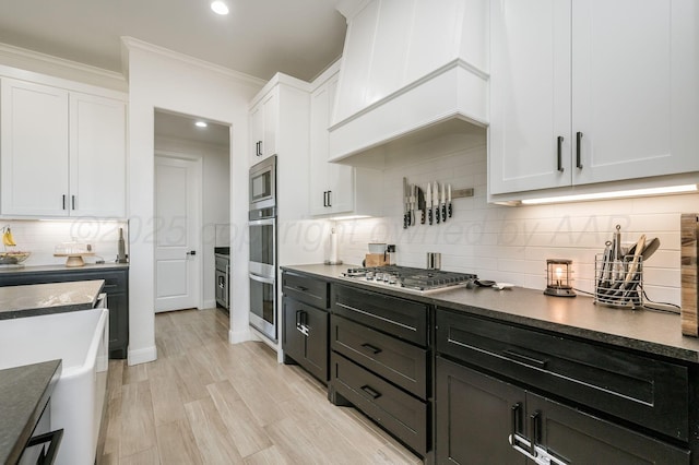 kitchen with crown molding, stainless steel appliances, dark countertops, decorative backsplash, and white cabinets