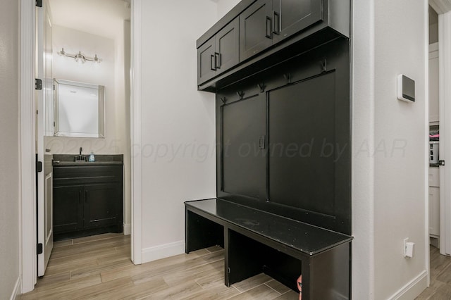 mudroom featuring light wood-style floors, a sink, and baseboards