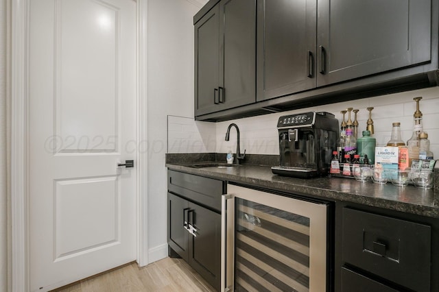 bar with light wood-style flooring, wine cooler, backsplash, a sink, and indoor wet bar