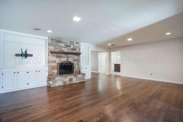 unfurnished living room with dark wood-type flooring and a stone fireplace