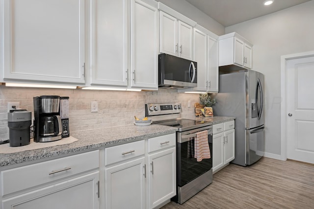 kitchen featuring white cabinetry, stainless steel appliances, backsplash, light wood-type flooring, and light stone countertops