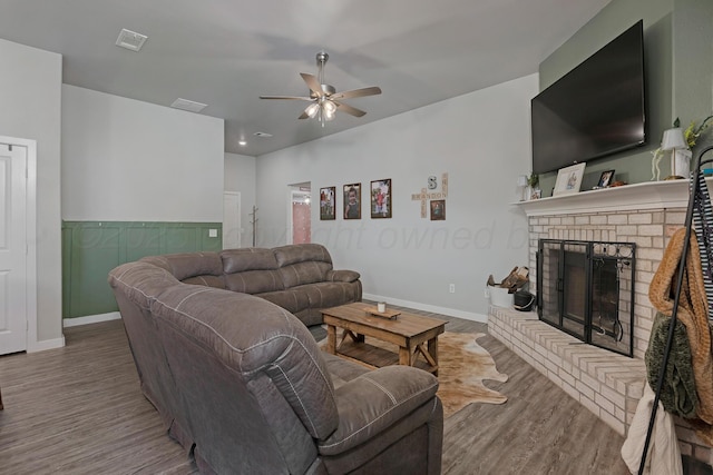 living room with a brick fireplace, hardwood / wood-style flooring, and ceiling fan