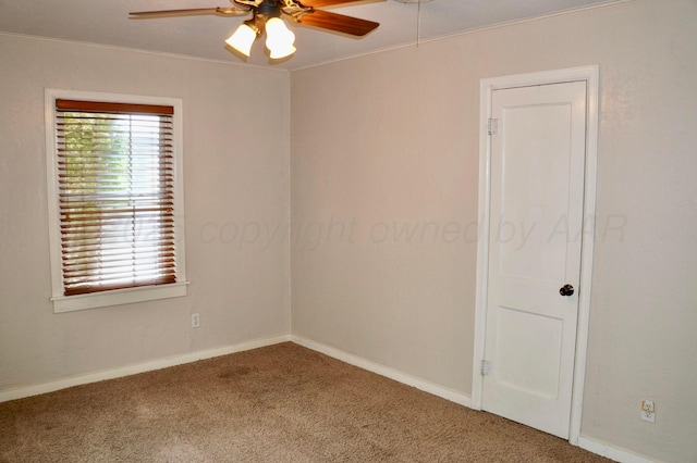 empty room with a ceiling fan, carpet floors, baseboards, and crown molding