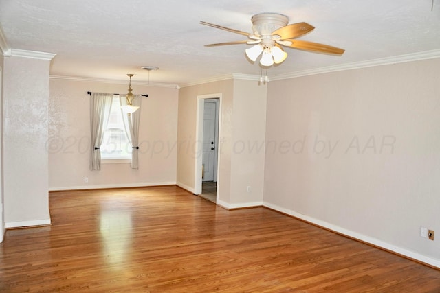 spare room featuring light wood-type flooring, ceiling fan, baseboards, and crown molding
