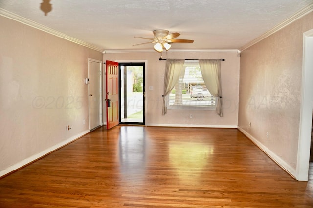 empty room featuring wood finished floors, ceiling fan, crown molding, and baseboards