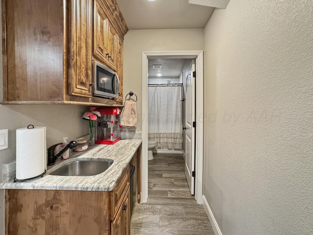 kitchen featuring dark hardwood / wood-style flooring, sink, and light stone countertops