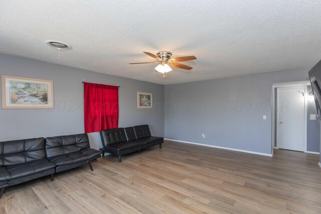 living room with light wood-type flooring, a textured ceiling, and ceiling fan