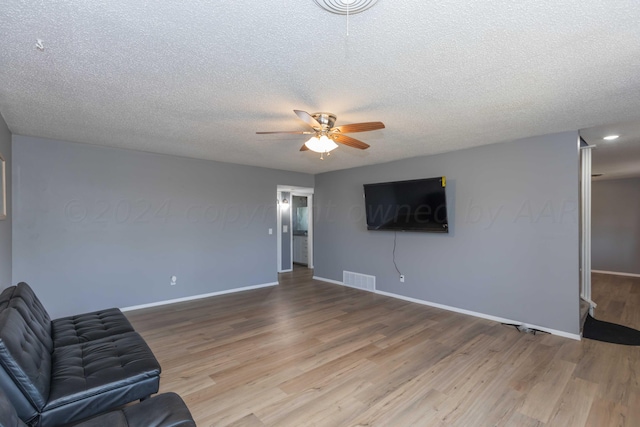 sitting room with wood-type flooring, ceiling fan, and a textured ceiling