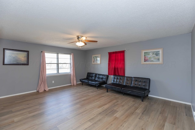 living room with a textured ceiling, light wood-type flooring, and ceiling fan