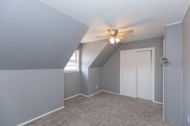 bonus room featuring ceiling fan, light colored carpet, a textured ceiling, and lofted ceiling