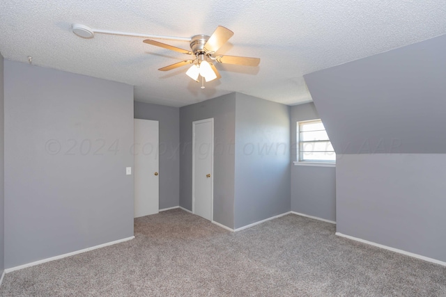 additional living space featuring a textured ceiling, light colored carpet, and ceiling fan