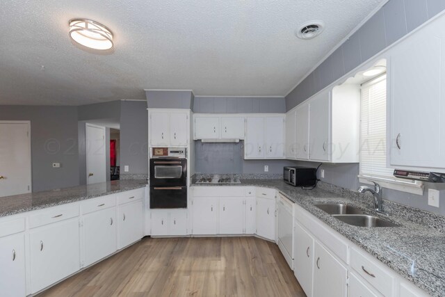 kitchen with stainless steel appliances, light wood-type flooring, a textured ceiling, sink, and white cabinets