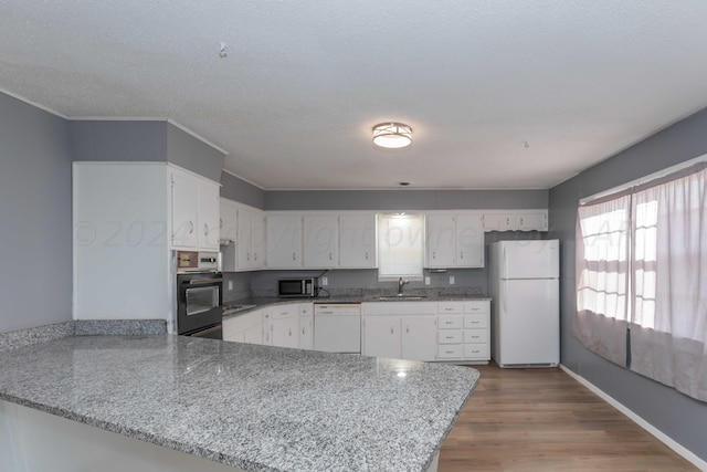 kitchen featuring kitchen peninsula, sink, light stone countertops, light hardwood / wood-style flooring, and white appliances