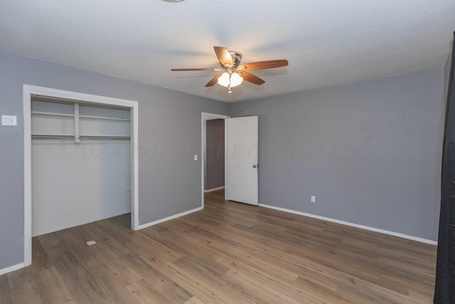 unfurnished bedroom featuring a textured ceiling, hardwood / wood-style floors, ceiling fan, and a closet