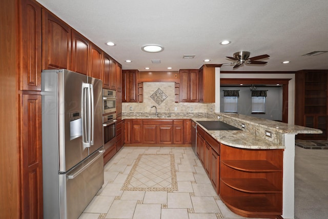 kitchen featuring appliances with stainless steel finishes, sink, decorative backsplash, kitchen peninsula, and light stone countertops