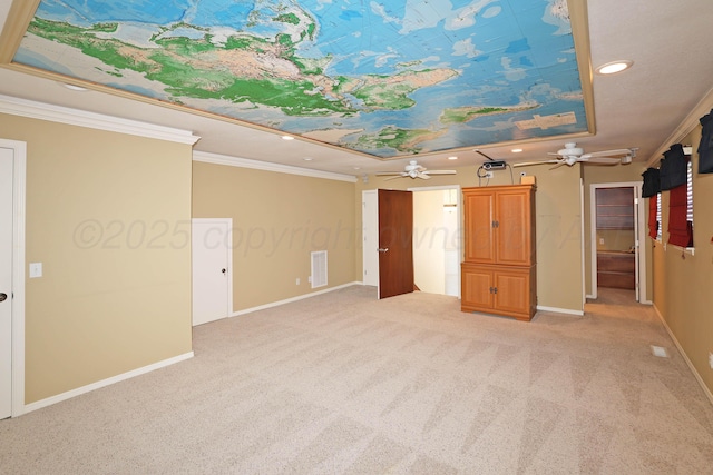 interior space featuring ceiling fan, light colored carpet, ornamental molding, and a tray ceiling