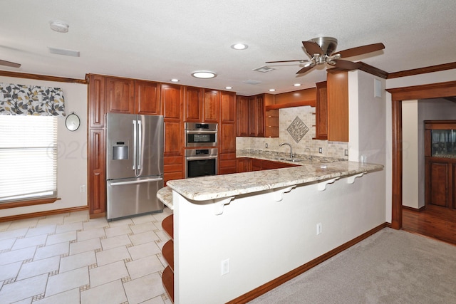 kitchen with tasteful backsplash, appliances with stainless steel finishes, a kitchen bar, and kitchen peninsula