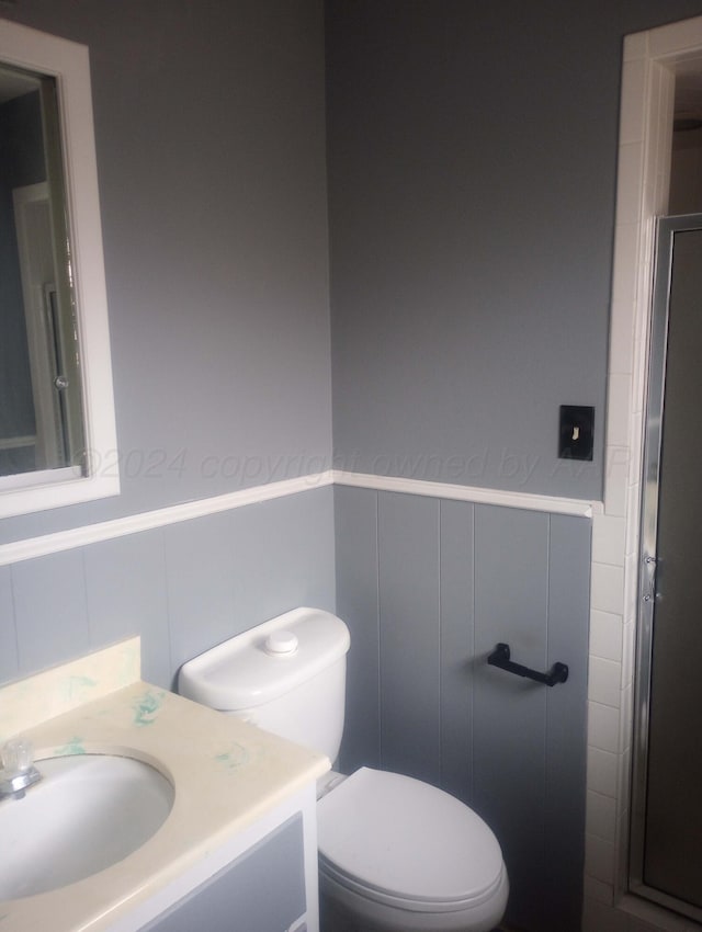 full bathroom with a stall shower, wainscoting, vanity, and toilet