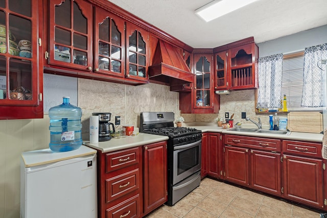 kitchen with premium range hood, sink, backsplash, fridge, and stainless steel gas range