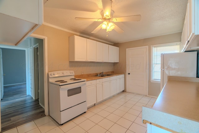 kitchen with white appliances, white cabinets, sink, light tile patterned floors, and a textured ceiling