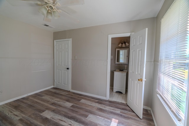 unfurnished bedroom with hardwood / wood-style floors, a closet, ensuite bathroom, and ceiling fan