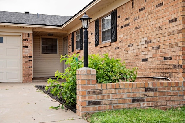 220 Hickory St, Hereford, TX 79045 - doorway to property with brick siding, roof with shingles, driveway, and a garage
