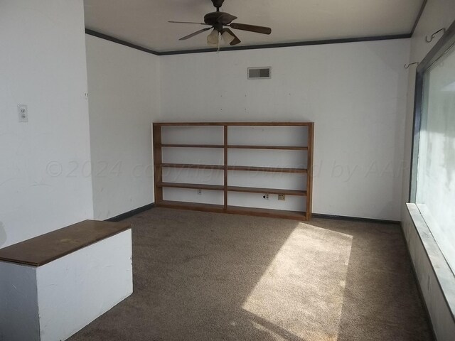 spare room featuring ceiling fan, crown molding, and dark carpet