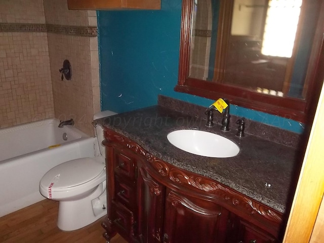 full bathroom featuring wood-type flooring, tiled shower / bath combo, toilet, and vanity