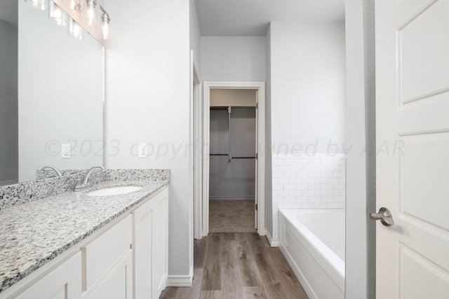 bathroom featuring hardwood / wood-style flooring, vanity, and a tub